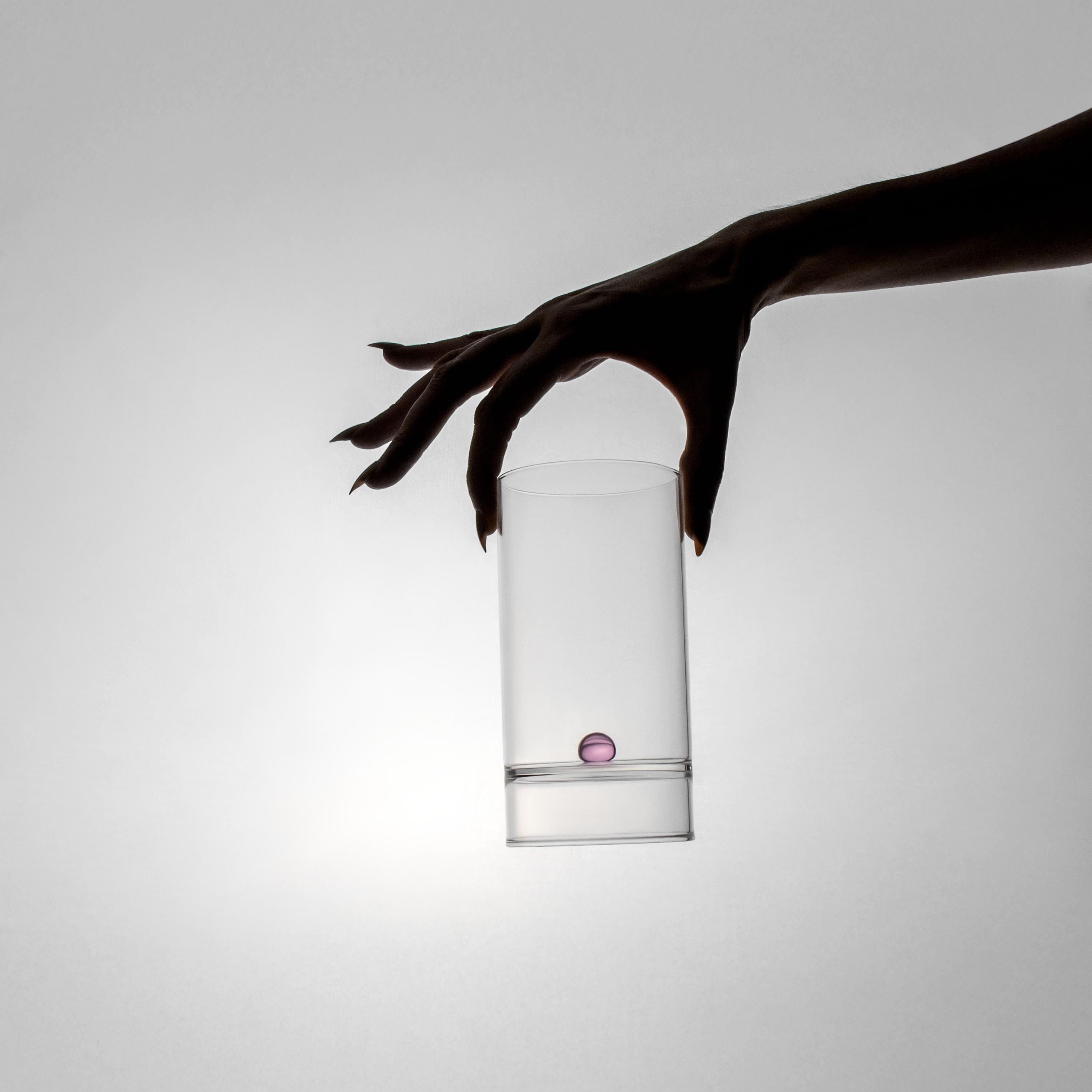 White cylindrical container held by a hand against a gray background