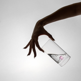 Hand holding a clear bottle with a pink label against a light gray background